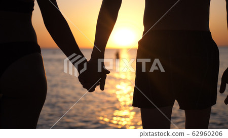 Couple holding hands each other and walking at sunset 62960206
