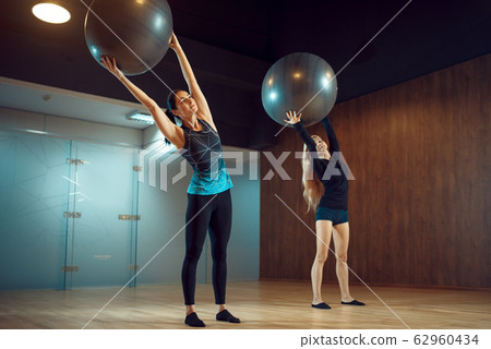 Two women, pilates training with balls in gym Two women, pilates training with balls in gym 62960434