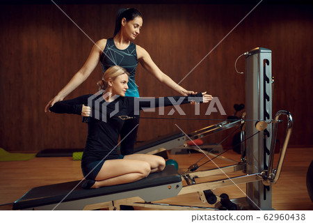 Slim woman on pilates training with instructor Slim woman on pilates training with instructor 62960438