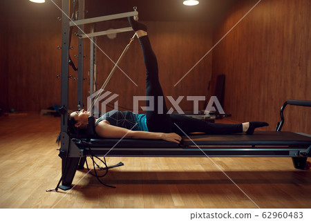 Slim woman doing stretching pilates exercise 62960483