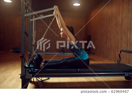 Woman doing stretching pilates exercise in gym Woman doing stretching pilates exercise in gym 62960487