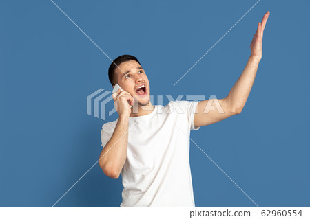 Caucasian young man's portrait on blue studio background Caucasian young man's portrait on blue studio background 62960554