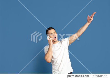 Caucasian young man's portrait on blue studio background Caucasian young man's portrait on blue studio background 62960556