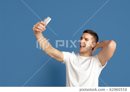 Caucasian young man's portrait on blue studio background 62960558