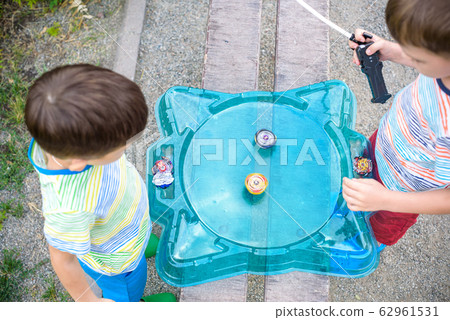 Two boys playing with a spinning top kid toy. 62961531
