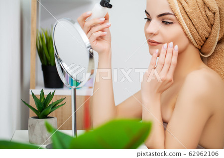 Woman getting ready for work doing morning makeup in bathroom mirror at home Woman getting ready for work doing morning makeup in bathroom mirror at home 62962106