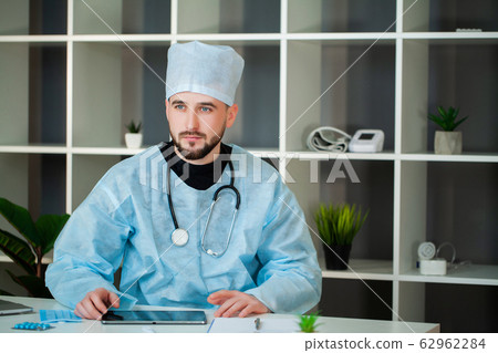 Doctor works at a table in the clinic's office. 62962284