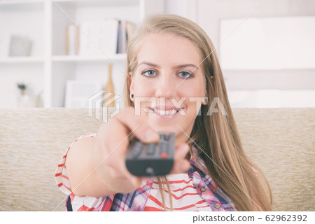 Woman holding tv remote control and changing TV Woman holding tv remote control and changing TV 62962392