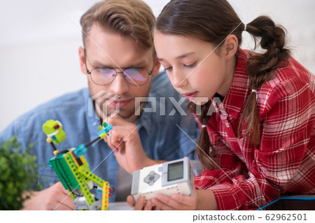Girl holding control unit, teacher sitting and touching chin Girl holding control unit, teacher sitting and touching chin 62962501