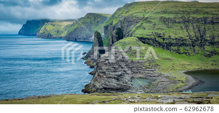 Steep coastline panorama in Faroe Islands with large boulders 62962678