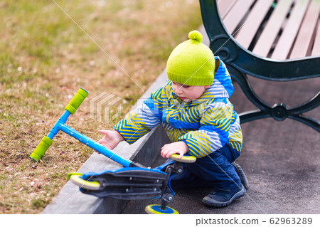 Cute little boy falling off his scooter Cute little boy falling off his scooter 62963289