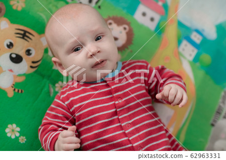 Cute little baby boy lying on his back smiling 62963331