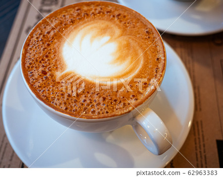 A cup of cappuccino on a table in a cafe. Drawing Heart on Latte coffee froth. View from above. Delicious coffee for breakfast A cup of cappuccino on a table in a cafe. Drawing Heart on Latte coffee froth. View from above. Delicious coffee for breakfast 62963383