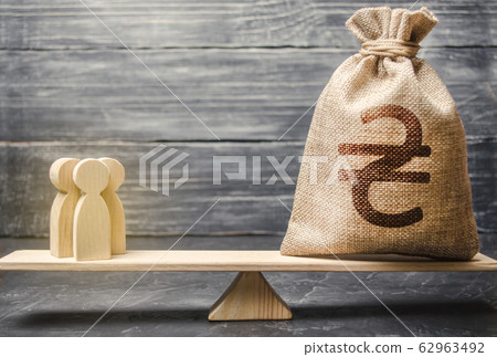 Ukrainian hryvnia UAH symbol on money bag and people on scales. concept attracting investment, business cooperation, crowdfunding startup. Staff salary specialist services cost. Solvency, taxpayers Ukrainian hryvnia UAH symbol on money bag and people on scales. concept attracting investment, business cooperation, crowdfunding startup. Staff salary specialist services cost. Solvency, taxpayers 62963492