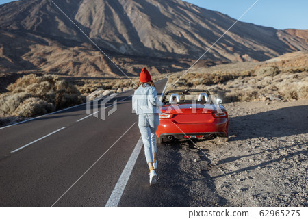 Woman traveling by car on a volcanic valley Woman traveling by car on a volcanic valley 62965275
