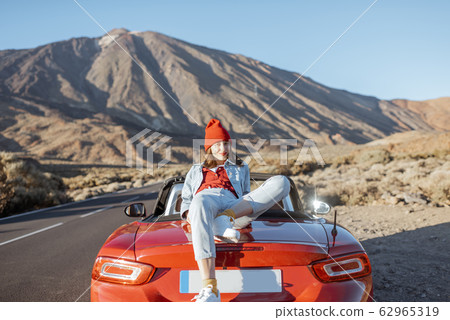 Woman traveling by car on a volcanic valley Woman traveling by car on a volcanic valley 62965319