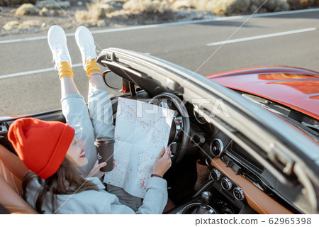 Woman traveling by convertible car on the desert valley Woman traveling by convertible car on the desert valley 62965398