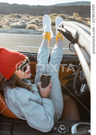 Woman traveling by convertible car on the desert valley Woman traveling by convertible car on the desert valley 62965400
