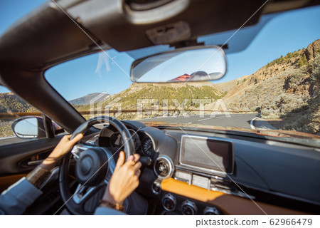 Woman driving a cabriolet on the mountain road 62966479