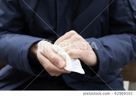 man disinfecting his hands with a wet wipe man disinfecting his hands with a wet wipe 62969101