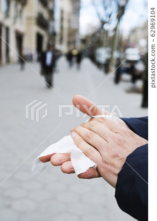 man disinfecting his hands with a wet wipe man disinfecting his hands with a wet wipe 62969104