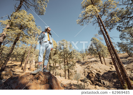 Woman hiking in the forest highly in the mountains on a volcanic rocks 62969485