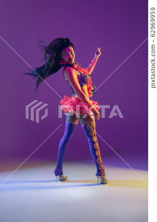 Attractive hawaiian brunette model on purple studio background in neon light Attractive hawaiian brunette model on purple studio background in neon light 62969959