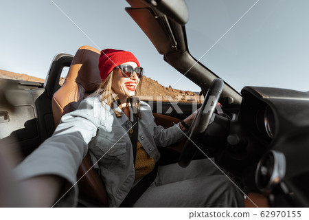 Woman traveling by cabriolet car on the desert road Woman traveling by cabriolet car on the desert road 62970155