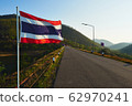 A Thailand flag waving against a mountain range. 62970241