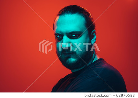 Portrait of a guy with colorful neon light on red background - cyberpunk concept Portrait of a guy with colorful neon light on red background - cyberpunk concept 62970588