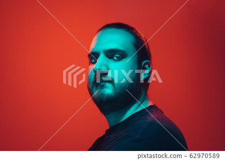 Portrait of a guy with colorful neon light on red background - cyberpunk concept Portrait of a guy with colorful neon light on red background - cyberpunk concept 62970589