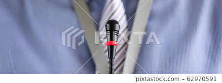 Man wearing necktie standing at conference microphone 62970591