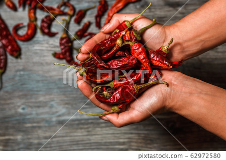 closeup dry mexican chilli pepper in hands over a wooden table closeup dry mexican chilli pepper in hands over a wooden table 62972580
