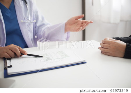 Female medicine doctor working on table with consulting patient Female medicine doctor working on table with consulting patient 62973249