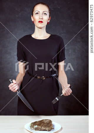 Young beautiful woman holding a knife and a fork 62973475