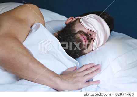 Caucasian bearded man in eyemask sleeping in bed 62974460