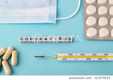 Word Coronavirus, surgical mask, thermometer and pills on a blue background. 62974635