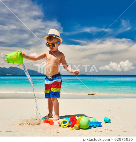 Three year old toddler playing on beach Three year old toddler playing on beach 62975030