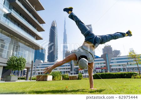 Acrobat keep balance on one hand with blurred Dubai cityscape. Concept of modern, business and Acrobat keep balance on one hand with blurred Dubai cityscape. Concept of modern, business and 62975444