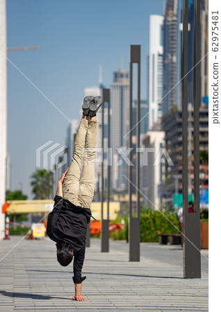 Acrobat keep balance one the hands with blurred Dubai cityscape. Concept of modern, business and 62975481