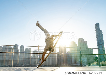 Cyr Wheel artist with cityscape background of Dubai during sunset Cyr Wheel artist with cityscape background of Dubai during sunset 62975493