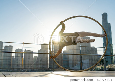 Cyr Wheel artist with cityscape background of Dubai during sunset Cyr Wheel artist with cityscape background of Dubai during sunset 62975495