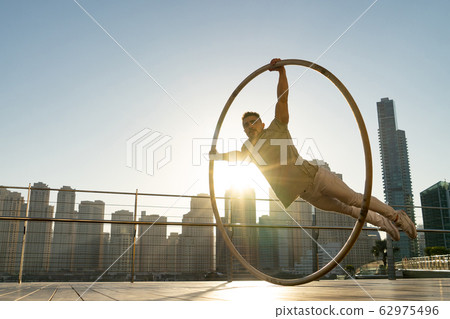 Cyr Wheel artist with cityscape background of Dubai during sunset Cyr Wheel artist with cityscape background of Dubai during sunset 62975496