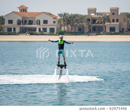 Water extreme sport. The guy is flying at the aquatic flyboard. Extreme rest on the sea 62975498
