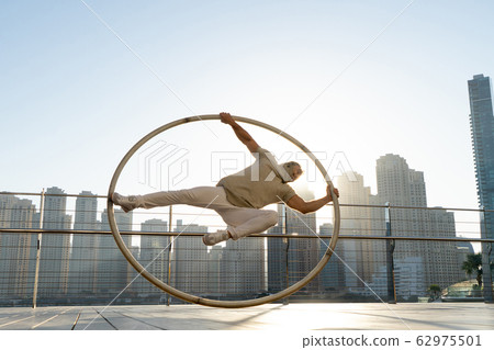 Cyr Wheel artist with cityscape background of Dubai during sunset Cyr Wheel artist with cityscape background of Dubai during sunset 62975501