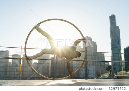 Cyr Wheel artist with cityscape background of Dubai during sunset Cyr Wheel artist with cityscape background of Dubai during sunset 62975512