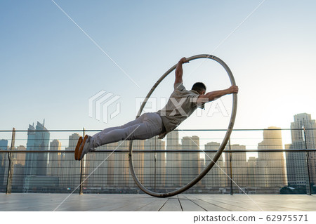 Cyr Wheel artist with cityscape background of Dubai during sunset Cyr Wheel artist with cityscape background of Dubai during sunset 62975571