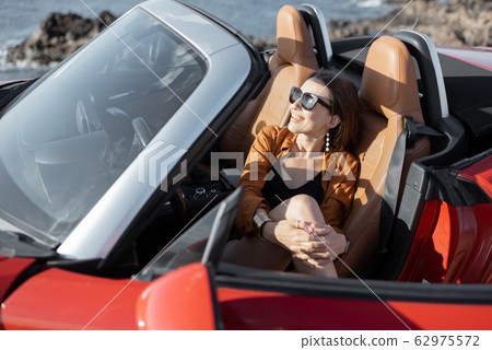 Woman enjoying summer vacation while traveling by car Woman enjoying summer vacation while traveling by car 62975572