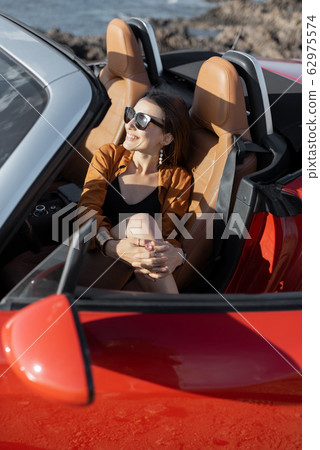 Woman enjoying summer vacation while traveling by car Woman enjoying summer vacation while traveling by car 62975574