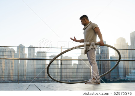 Cyr Wheel artist with cityscape background of Dubai during sunset Cyr Wheel artist with cityscape background of Dubai during sunset 62975576
